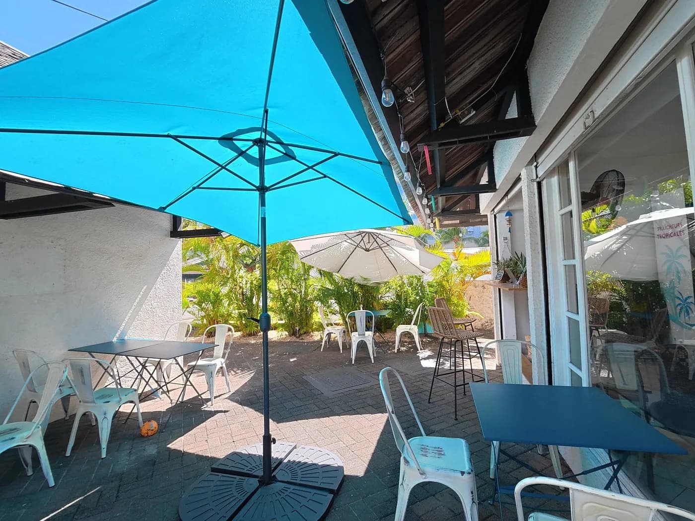 La terrasse ombragée d'Éclats d'Éden, tables turquoise sous les parasols